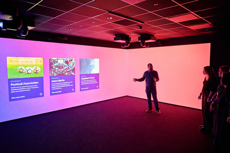 Several individuals gather in front of a large screen
